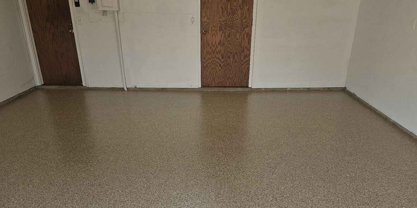 The same Wayzata garage floor finished in Hickory decorative flake, covering wall to wall with a coved edge where the floor meets the wall